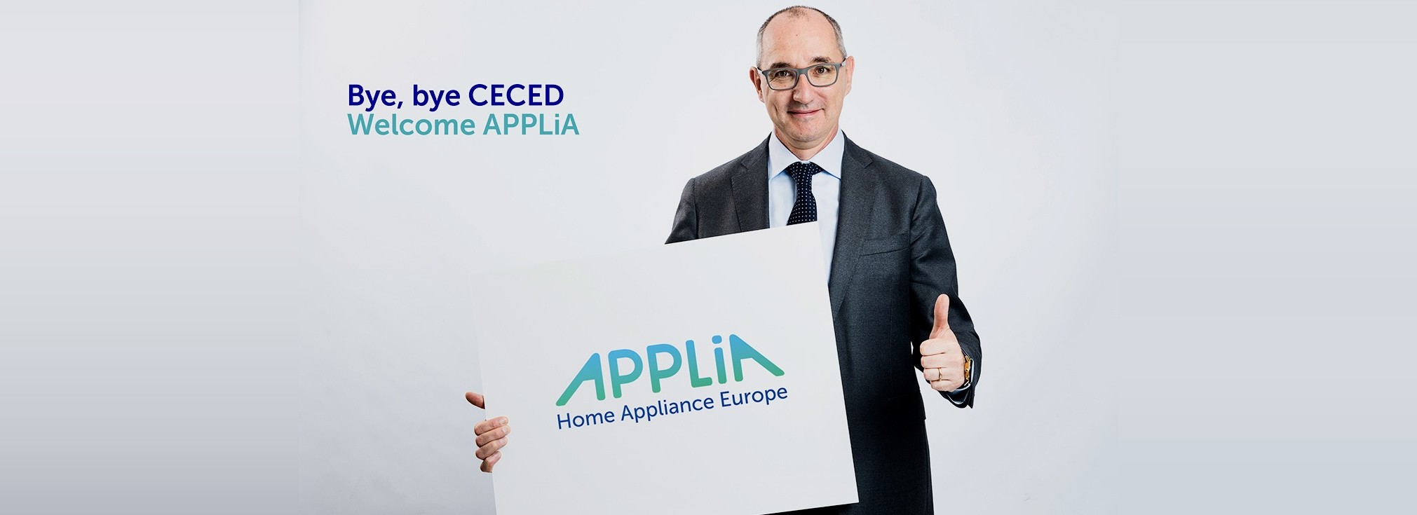 APPLiA rebranding by #inextremis: a man in a suit holding a large sign with the new APPLiA Home Appliance Europe logo, beside the message Bye, bye CECED — Welcome APPLiA