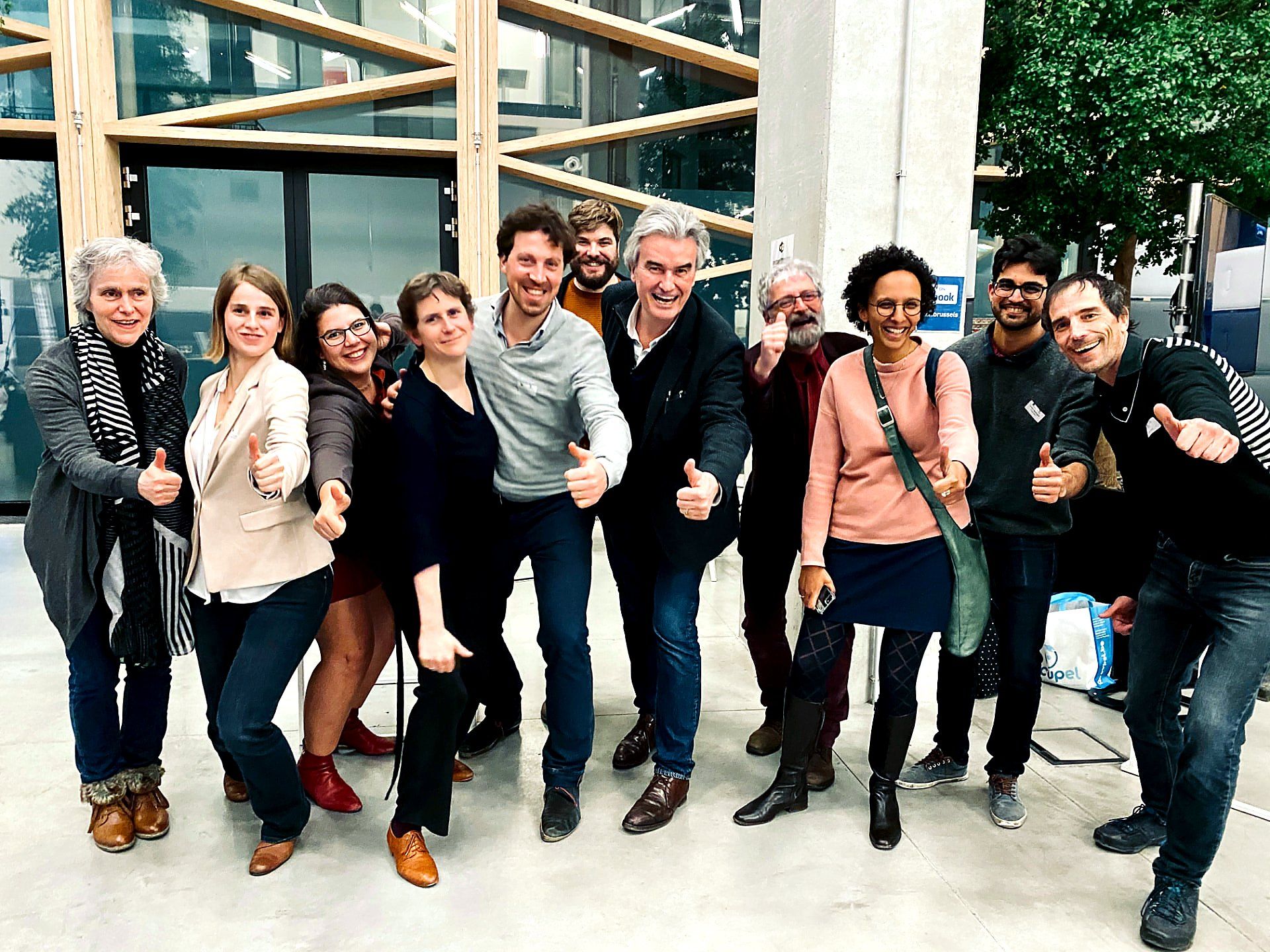 The #inextremis team and client group giving a thumbs-up together in a bright Brussels venue after a completed assignment